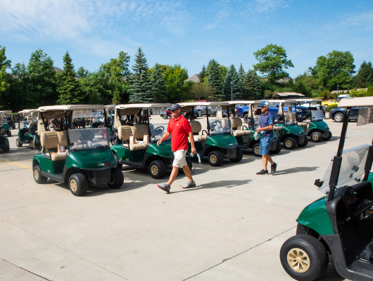 lines of golf carts and men walking by